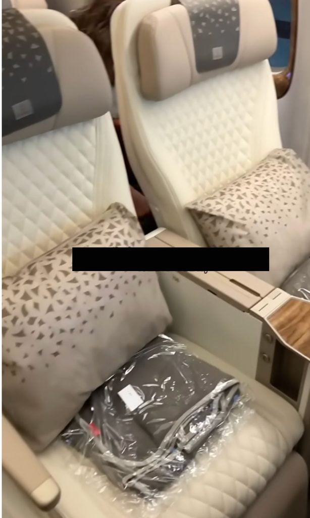 A travel influencer showing their premium economy leather seats on an Emirates flight; is travel hacking worth it